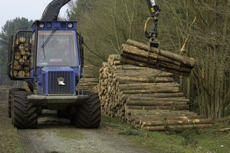 Machine removing felled trees in a woodland
