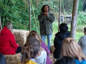 Team Wilder Community Campfire Elsie Harp speaking with green natural background under a canvas with people