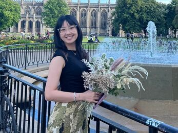 A woman holding flowers in front of a fountain and cathedral