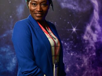 A woman with a blue jacket and purple galaxy background