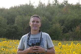 Iolo stands in a field of sunflowers