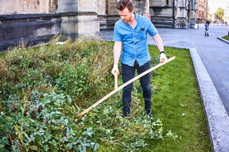 Volunteer at work scything at College Green