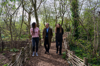 Chantelle Lindsay, Dr Simon Thurley and Bobbi Benjamin-Ward walking on a woodland path