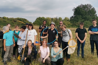 A group of young volunteers gather together, holding butterfly catching nets