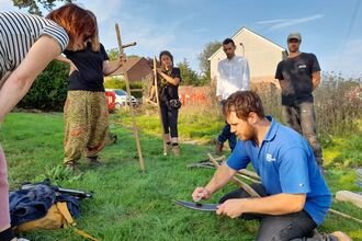 Community event with residents and a male ecologist on grass in a village green planting