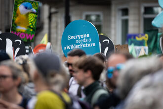 People on a march, you can see a sign which reads 'Everyone needs a wilder future'