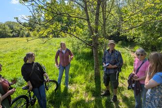 Local residents listening to an ecologist while stood in a field on a sunny day