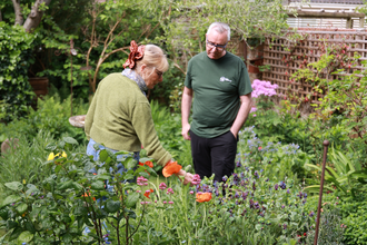 Lou points to some wildflowers as she show Stuart, who is wearing an Avon Wildlife Trust t-shirt, around her garden
