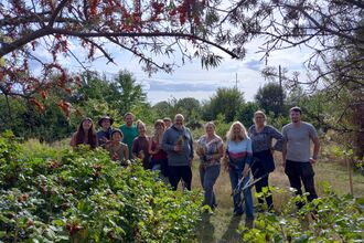 A group of people outdoors with trees and bushes framing the picture on a sunny day