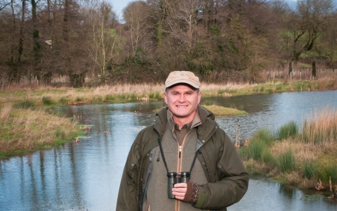 Simon King standing in front of a pond