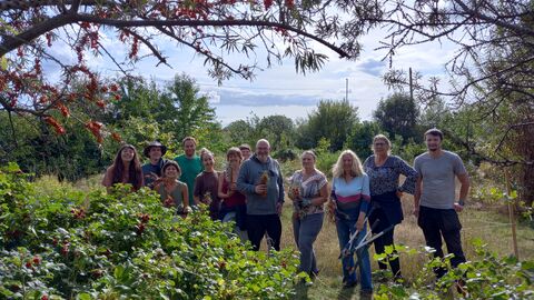 A group of people outdoors with trees and bushes framing the picture on a sunny day