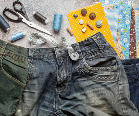 Sewing equipment laid out next to a pair of jeans, ready to be mended