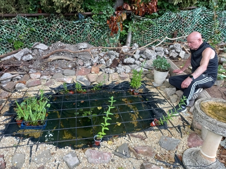 A man sitting next to a pond