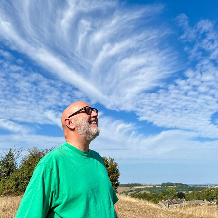 Andrew Grant headshot, outdoors with clouds above