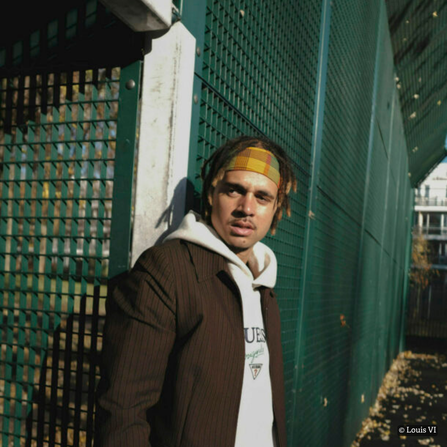 A young man with a head band and a hoody on stood in front of gates