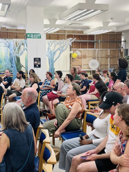 An audience of people listening to panelists at the Community Gathering event