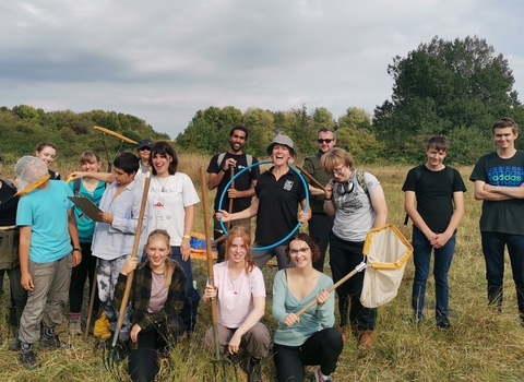 A group of young volunteers gather together, holding butterfly catching nets