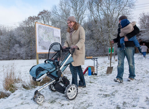 Family with pushchair walking in the snow