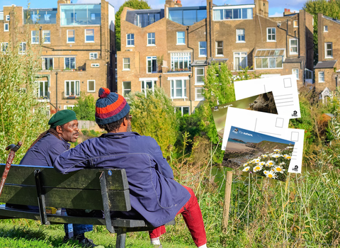 Two men talking on a bench overlooking terraced housing, and superimposed postcard images